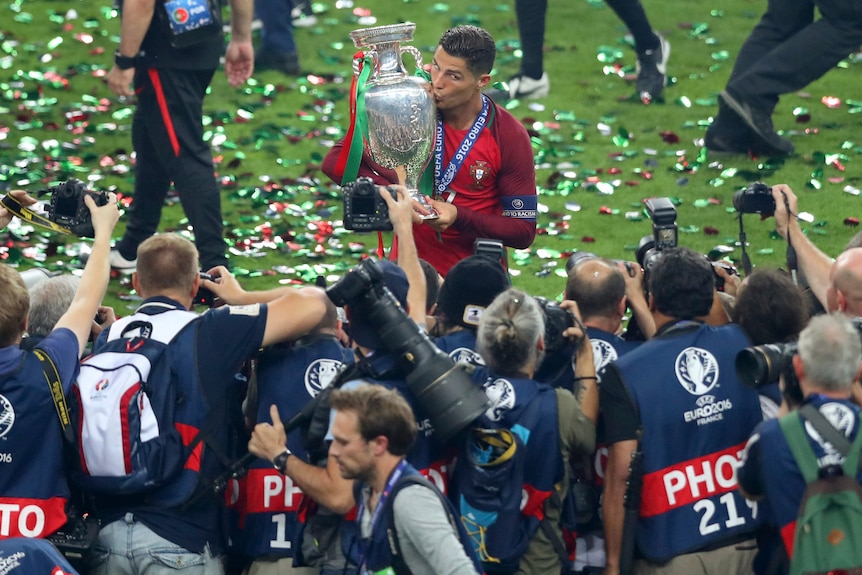 Cristiano Ronaldo holds a trophy in front of camera