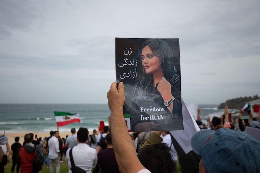 A protester holds a poster which says 'freedom for Iran' with a picture of a young girl in a hijab