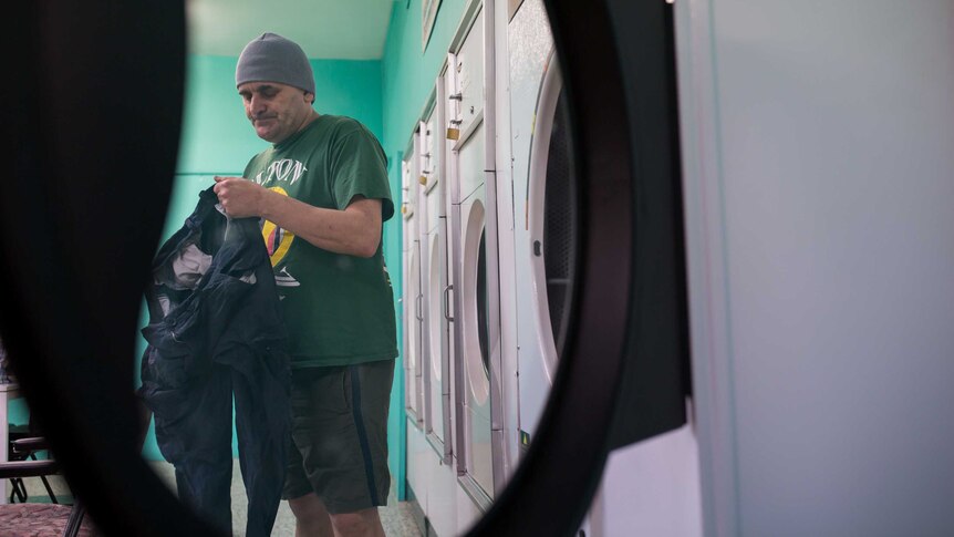 A man removes his washing from a dryer
