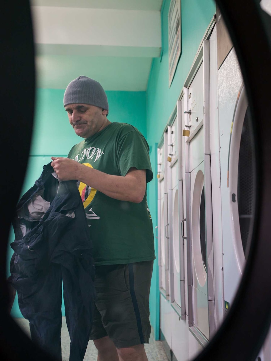 A man removes his washing from a dryer