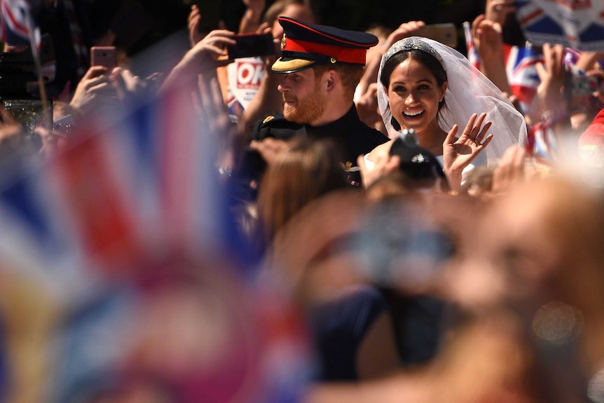 Prince Harry, Duke of Sussex and his wife Meghan, Duchess of Sussex wave at their wedding.