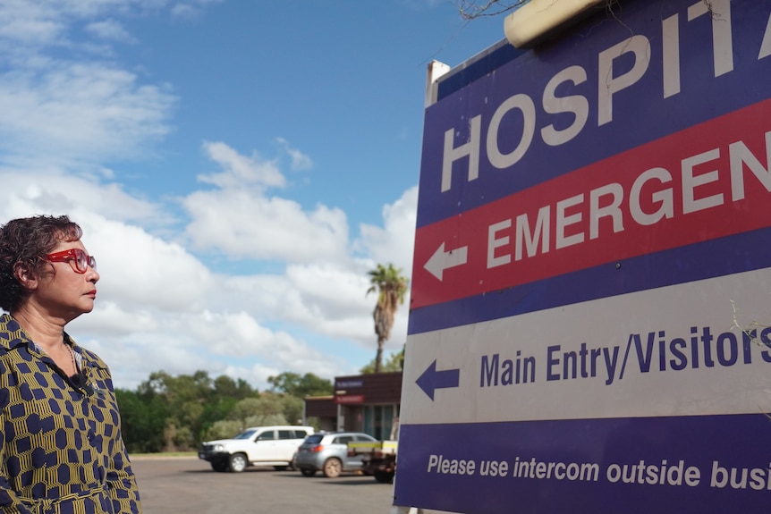 Ashburton Shire President Audra Smith looks at a blue and red sign at Tom Price hospital.