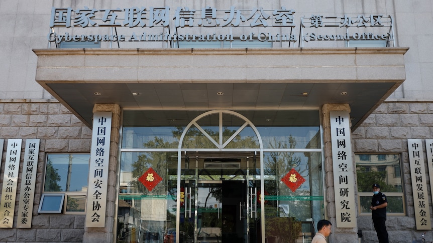 A man walking in front of a building with chinese writing and the words "Cyberspace Administration of China."