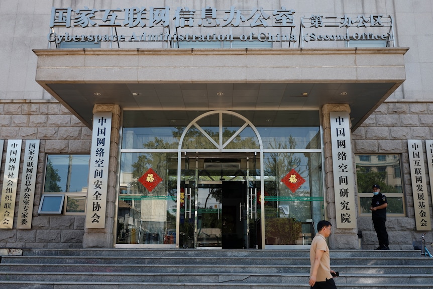 A man walking in front of a building with chinese writing and the words "Cyberspace Administration of China."