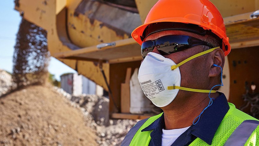 A man wearing a white face mask and sunnies.