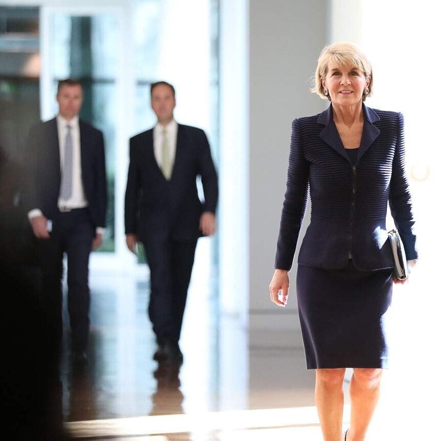 Julie Bishop walks down a well lit hall, with a positive expression on her face.