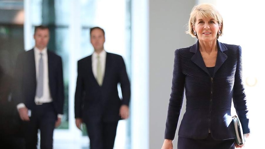 Julie Bishop walks down a well lit hall, with a positive expression on her face.