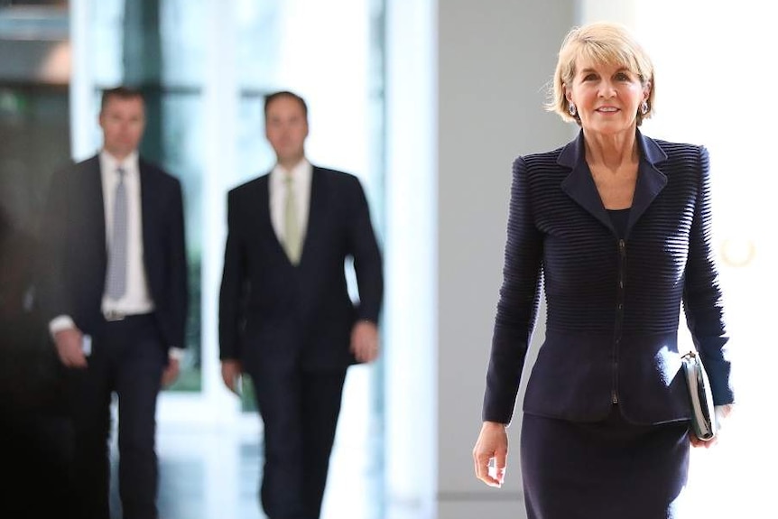 Julie Bishop walks down a well lit hall, with a positive expression on her face.