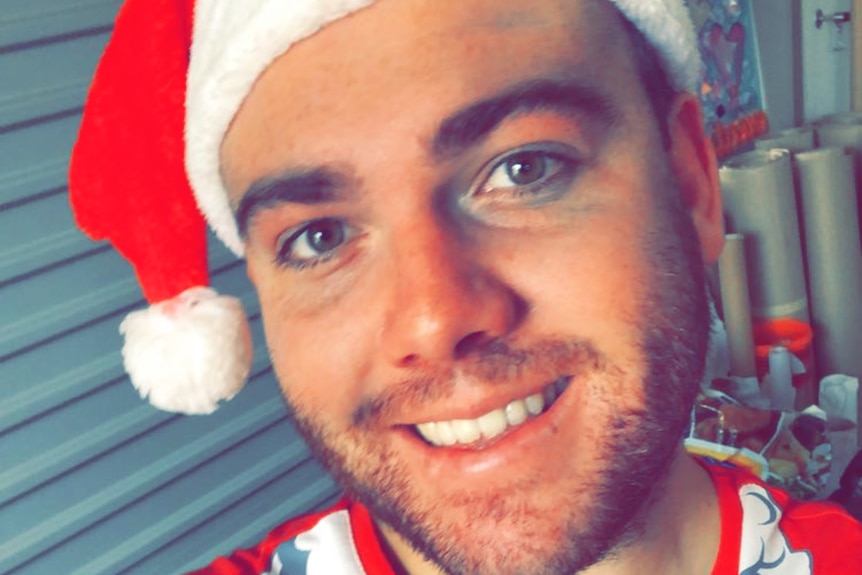 A smiling young man in a Santa hat.