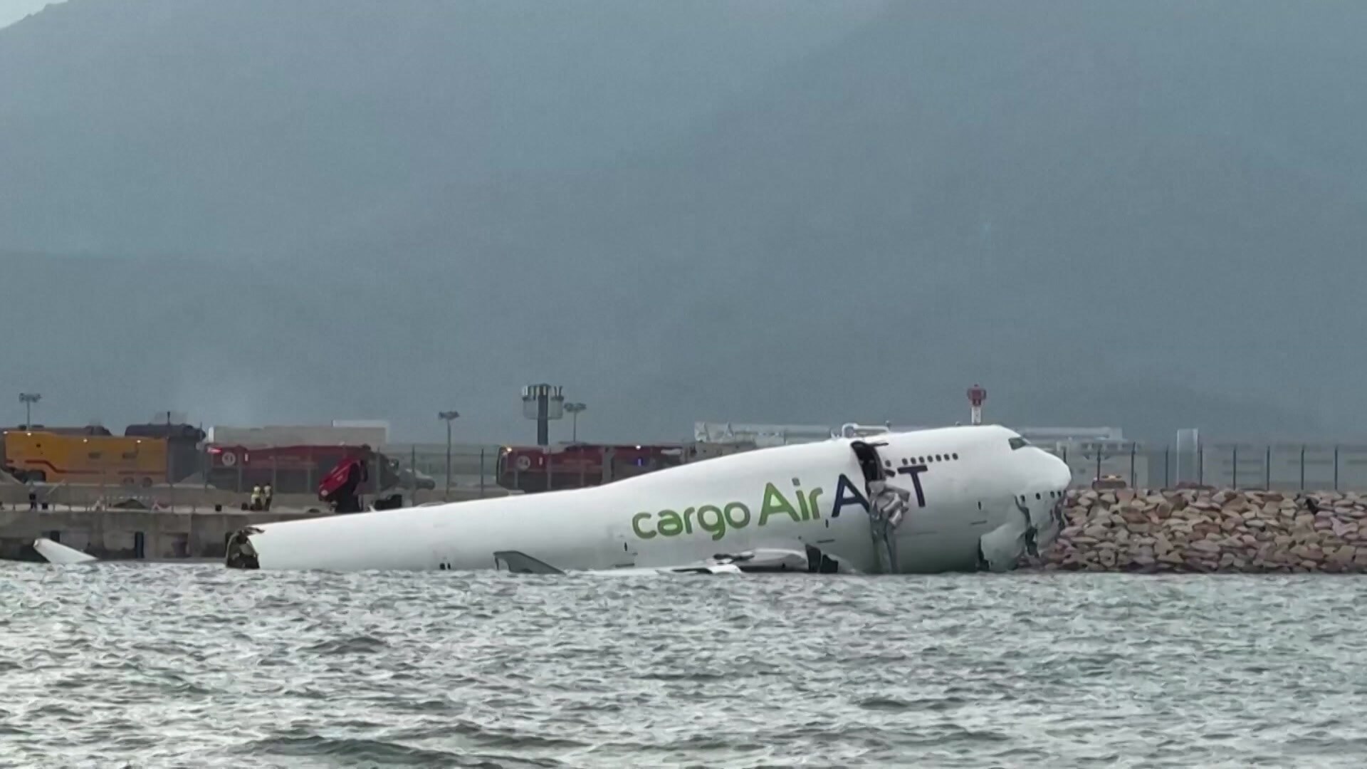The front end of a plane in the water after skidding off the runway. 