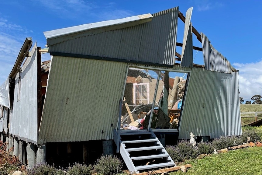 A corrugated iron building with the front wall hanging at an angle.