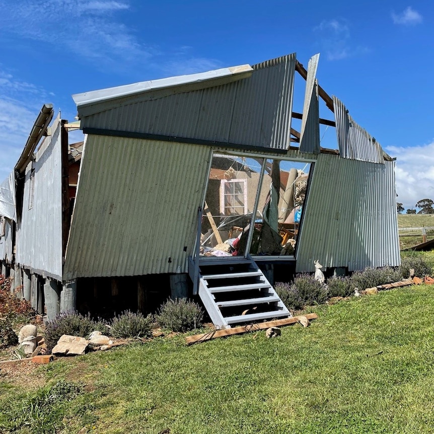 A corrugated iron building with the front wall hanging at an angle.