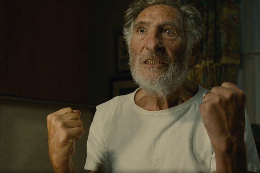 A still of Judd Hirsch in The Fabelmans, with his fists clenched and a tense expression. 