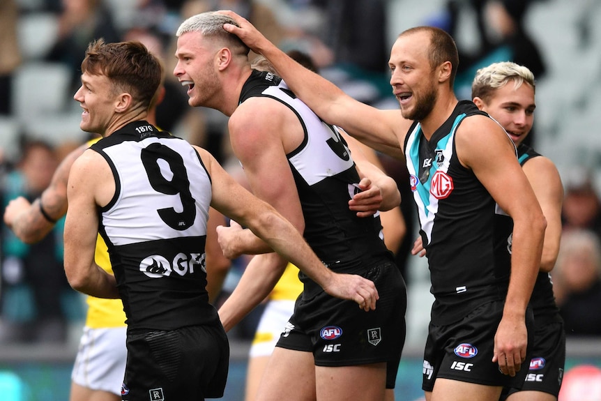 Four Port Adelaide Power AFL players celebrate the scoring of a goal against Richmond.