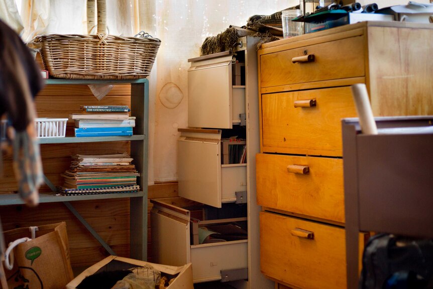 A messy room full of shelves and filing cabinets.