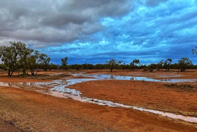 rain puddles in red earth with a cloudy sky above