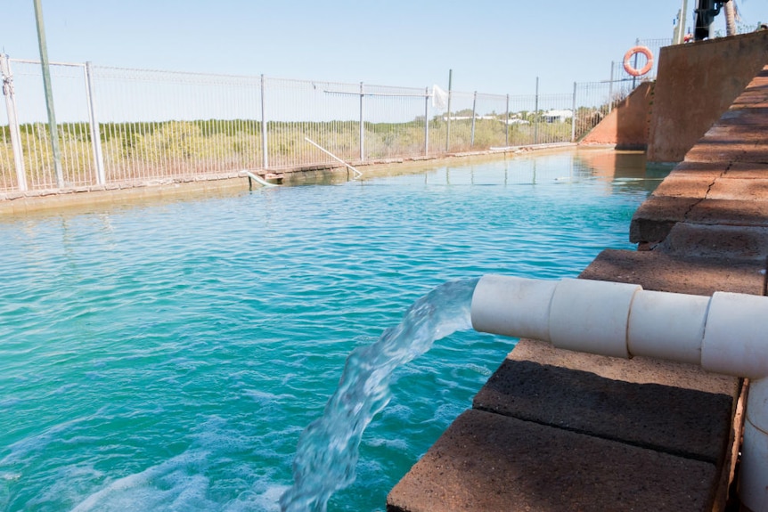 Water pours from a pipe into a pool.