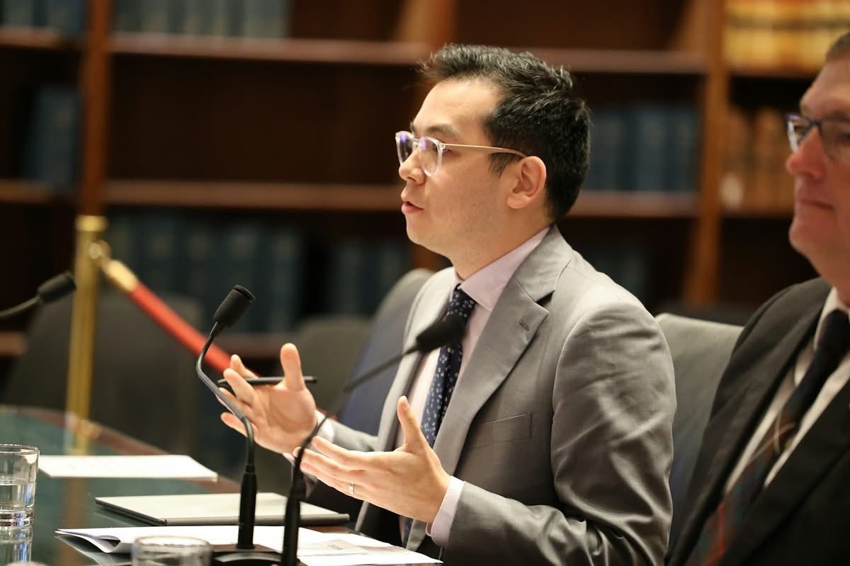 A man gestures while speaking at a lectern.