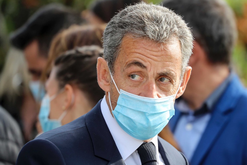 Nicolas Sarkozy looks to his right while wearing a face mask
