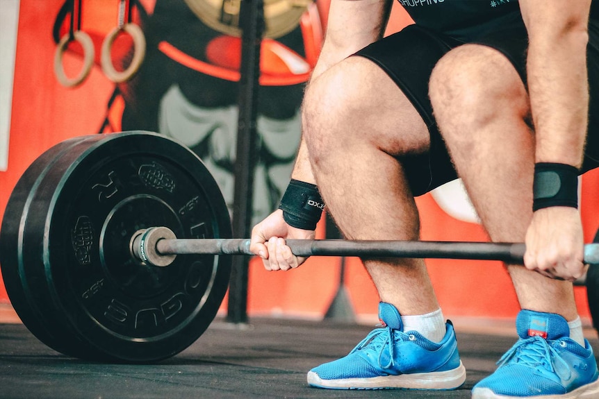 A man lifting weights in the gym to depict how often to wash everyday items like towels and bras.