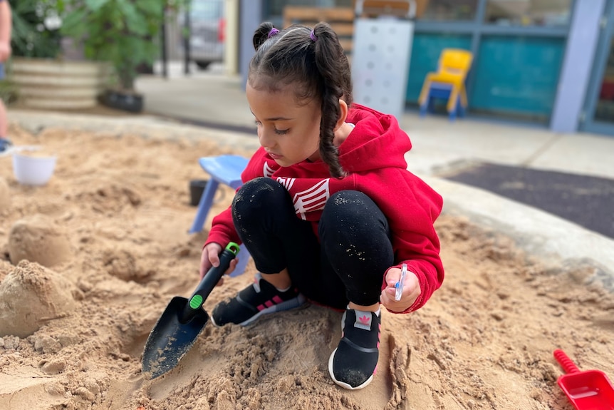 A girl plays in a sandpit 