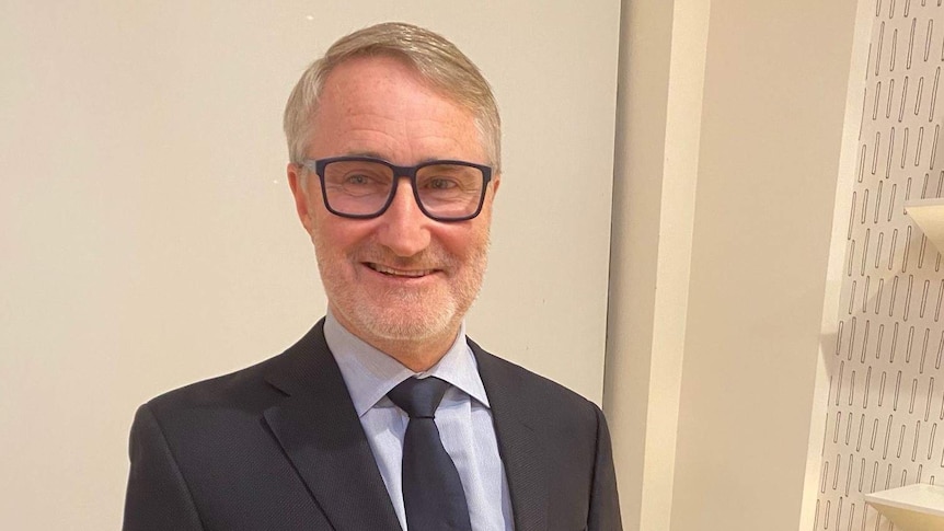 A man in a suit with glasses smiling