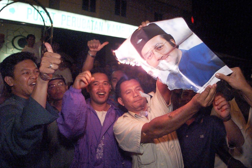 Supporters of Anwar Ibrahim burn a portrait of Mahathir Mohamad