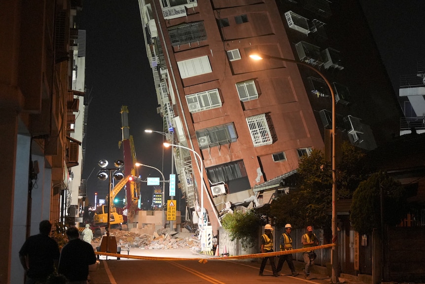 Workers walk at the site where a building collapsed