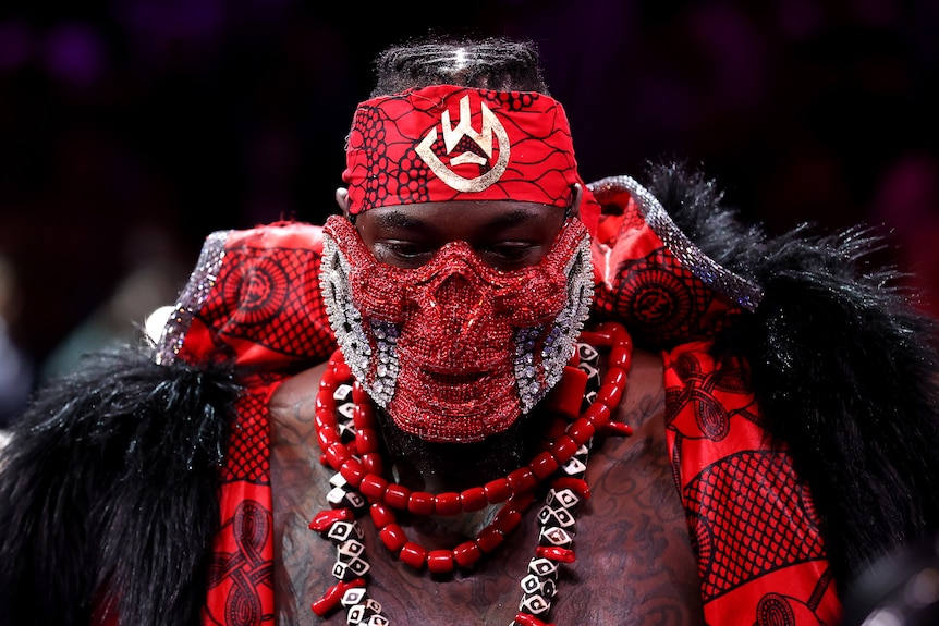 Deyontay Wilder wears a red sequined mask, red bandanna and fur cape
