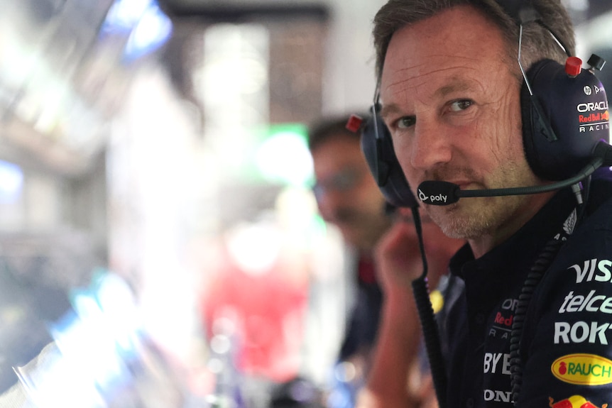 Christian Horner, sitting in the pits, with his head piece on, at the computer.