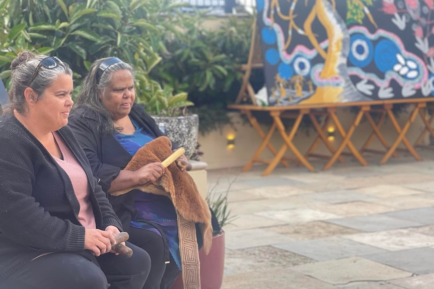 Two Indigenous women sitting next to each other in a beer garden.