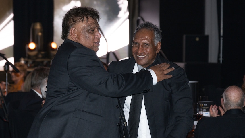 Two men hugging at a presentation night