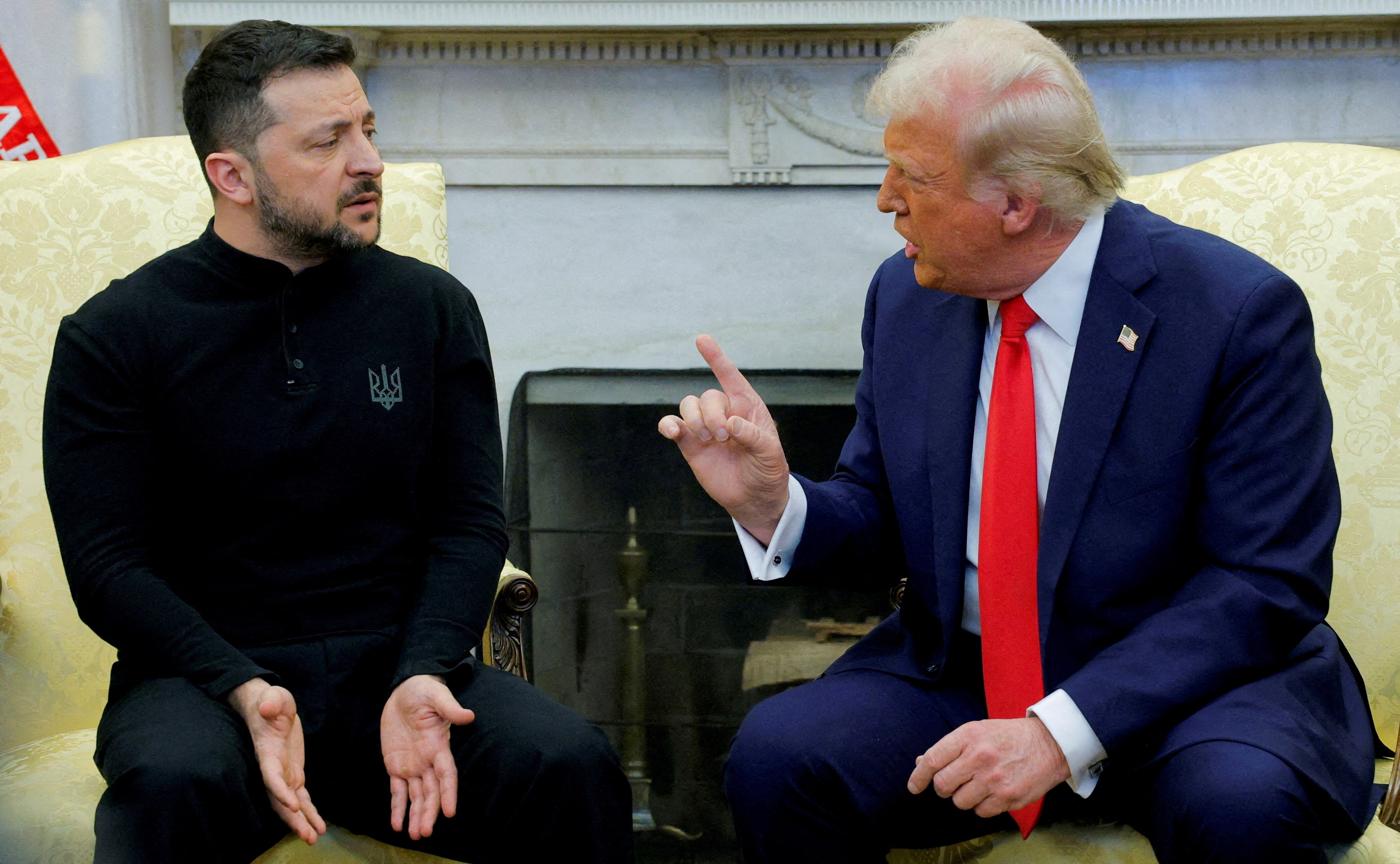 Donald Trump raising a pointed finger towards Volodymyr Zelenskyy sitting next to him in the oval office appearing bemused