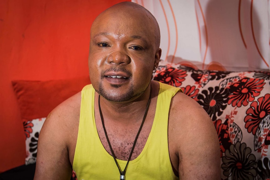 Mama G sits on his couch in his apartment in Nairobi