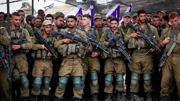 A row of men, dressed in combat gear, holding machine guns