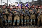 A row of men, dressed in combat gear, holding machine guns