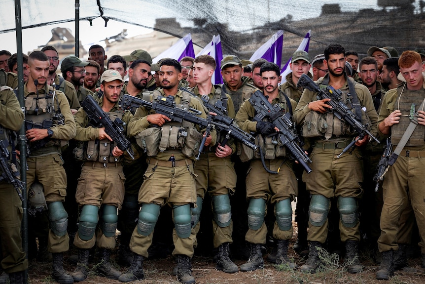 A row of men, dressed in combat gear, holding machine guns