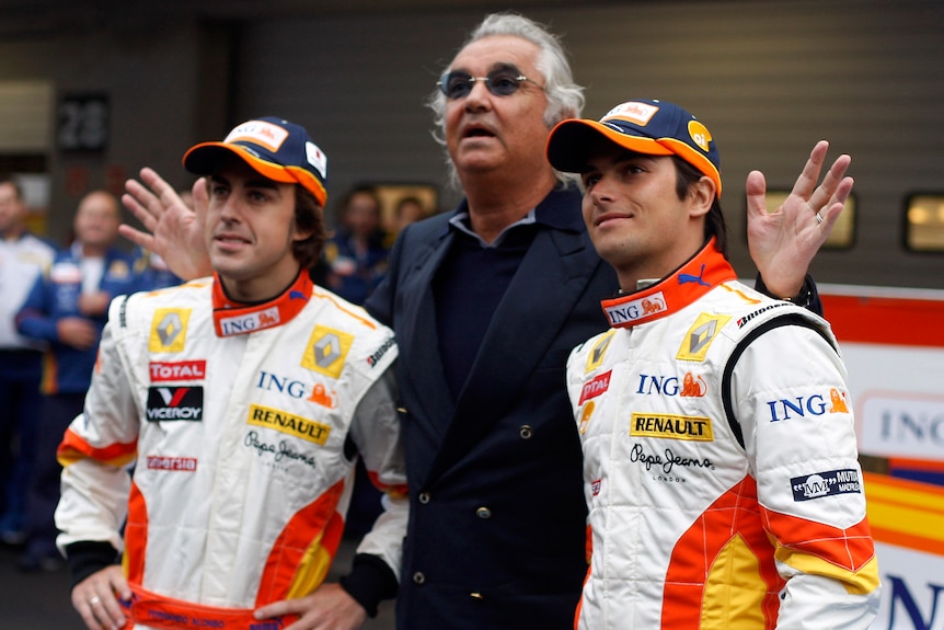 Two race drivers with their team boss in the centre, smile for cameras during a media event