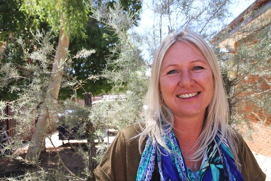 Aileron Station owner Sarah Cook smiling in a rural backyard.