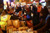 People queue up as volunteers serve out food donations to those in need in London, November 2020.