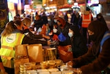 People queue up as volunteers serve out food donations to those in need in London, November 2020.