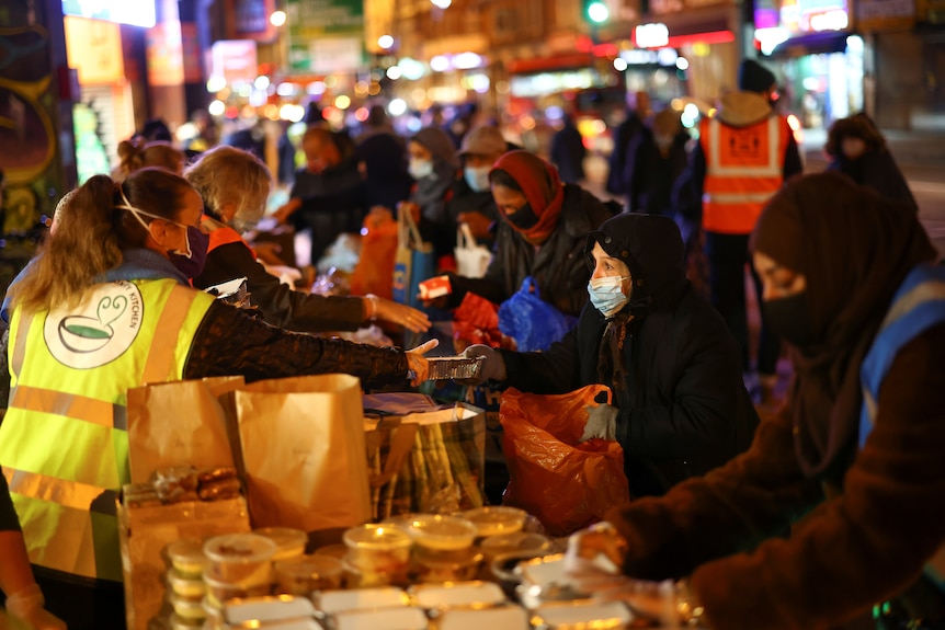 People queue up as volunteers serve out food donations to those in need in London.