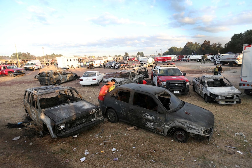 People examine burnt cars among the wreckage following the explosion at the San Pablito firworks market, December 20, 2016.