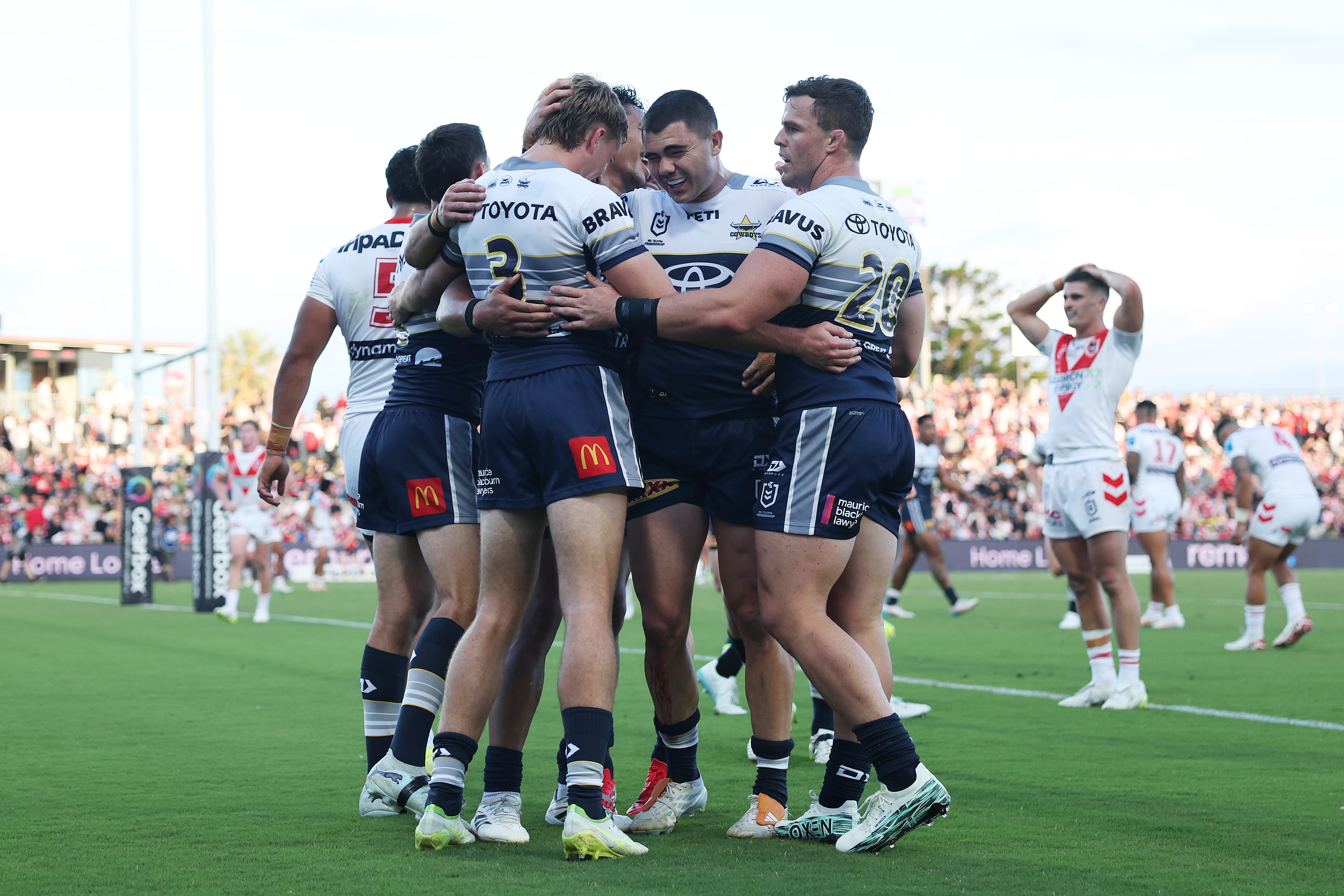 A group of rugby league players huddle in celebration