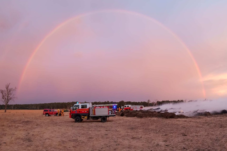 A rainbow over a firetruck in a field