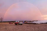 A rainbow over a firetruck in a field