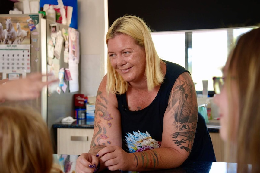 A mother in a kitchen laughing with her children