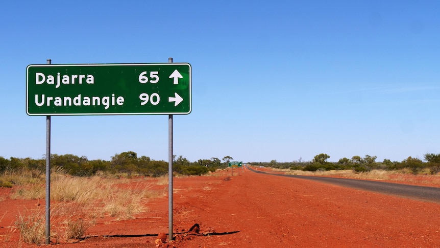 Road sign reads 'Dajarra' amid desert country and blue sky