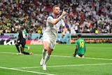 An England player runs away from goal holding a finger in the air in celebration after scoring a goal.