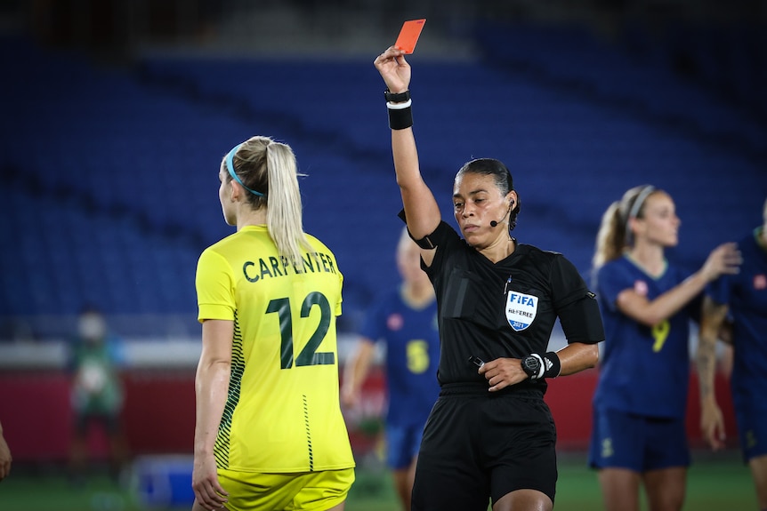 A women wearin black holds up a red card in front of a women wearing yellow